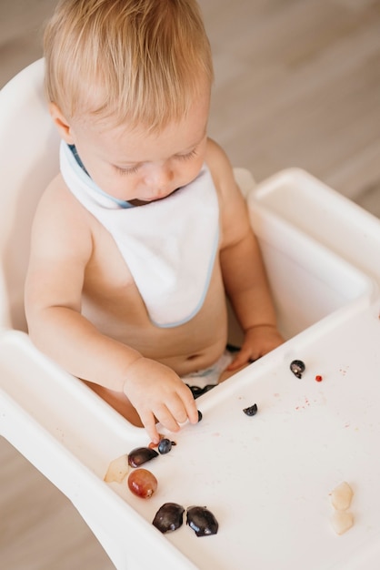 Free photo smiley cute baby boy eating alone