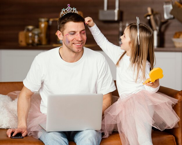 그는 노트북에서 작업하는 동안 아버지와 놀고 웃는 딸