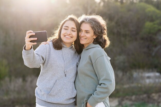 Free photo smiley daughter taking a selfie with her mother outdoors