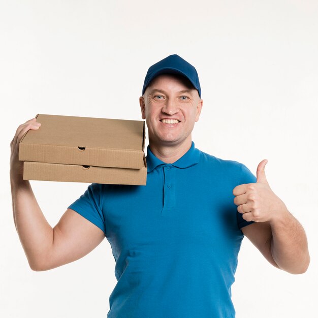 Smiley delivery man giving thumbs up while carrying pizza boxes