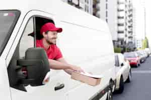 Free photo smiley delivery man handing package