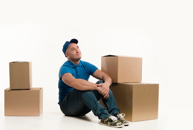 Free photo smiley delivery man posing with cardboard boxes