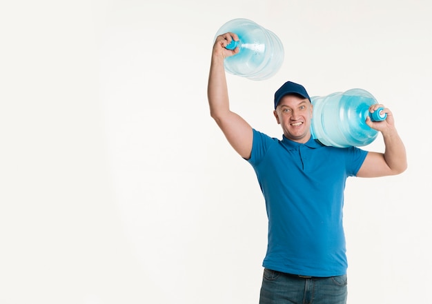 Smiley delivery man posing with water bottles and copy space