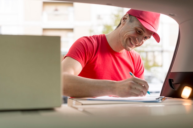 Smiley delivery man signing document