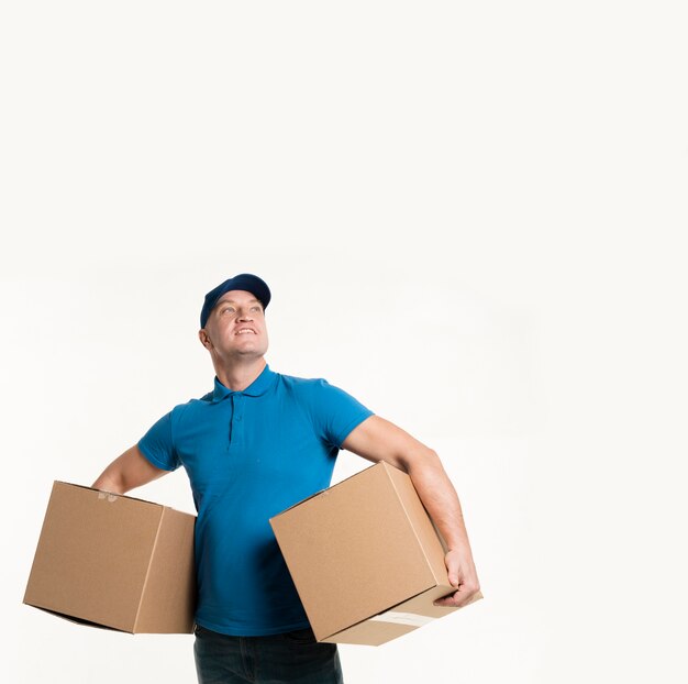 Smiley delivery man with cardboard boxes in arms and copy space