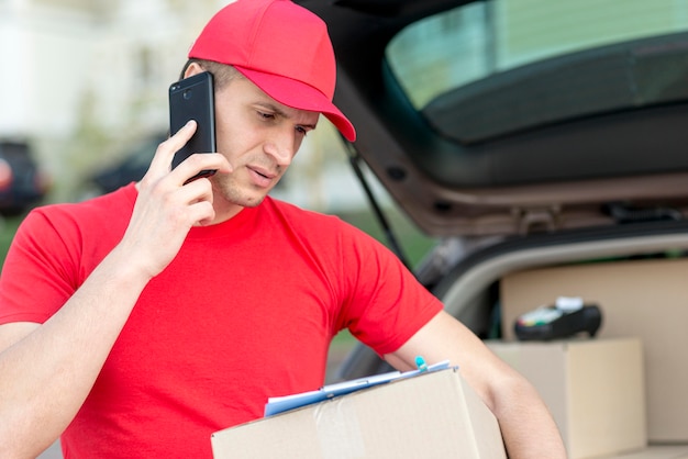 Free photo smiley delivery man with phone