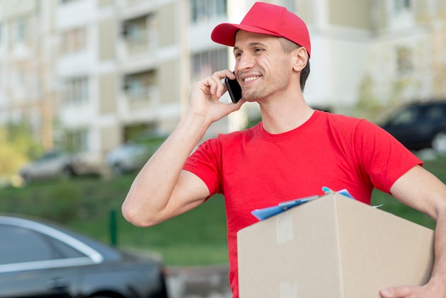 Smiley delivery man with smartphone