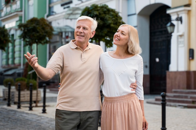 Free photo smiley elder couple taking a walk outdoors in the city