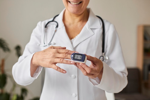 Oximeter를 사용하는 웃는 노인 COVID 회복 센터 여성 의사