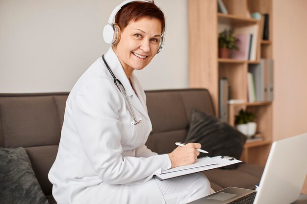 Smiley elder covid recovery center female doctor with headphones and clipboard