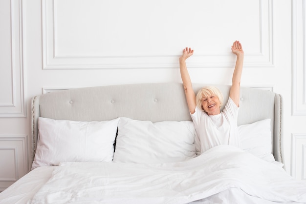 Free photo smiley elder woman laying in the bedroom