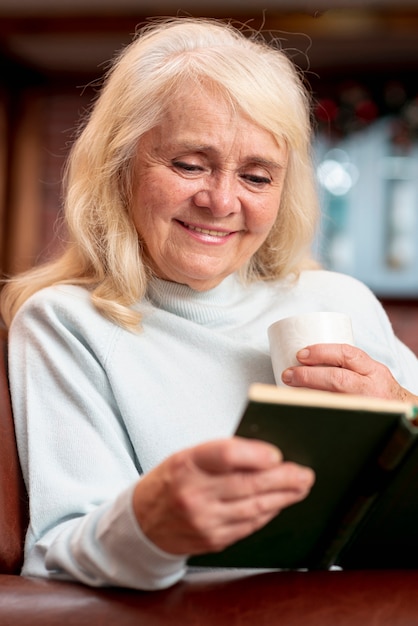 Free photo smiley elder woman reading