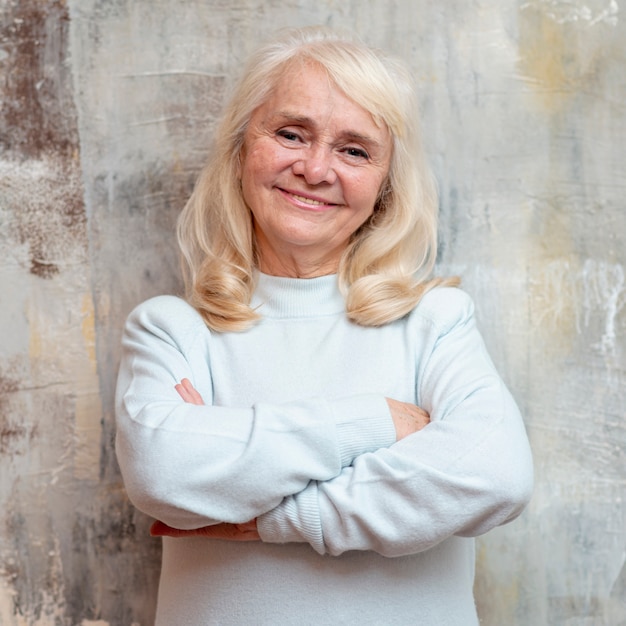 Free photo smiley elder woman standing next to frozen window