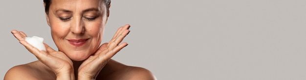 Smiley elder woman with foaming cleanser in her hand and copy space