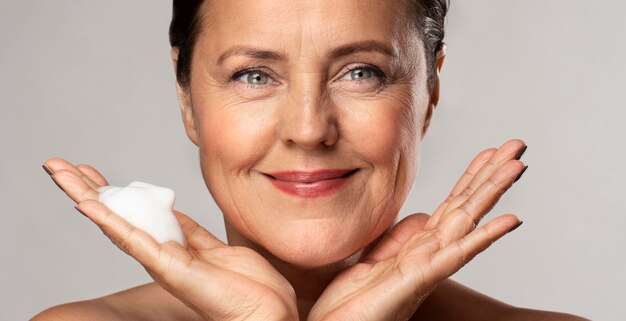 Smiley elder woman with foaming cleanser in her hand