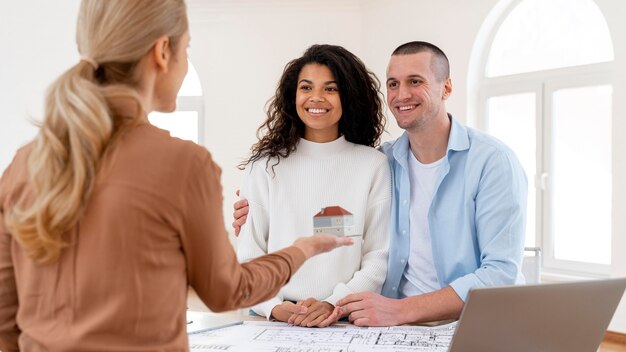 Smiley embraced couple conversing with female realtor