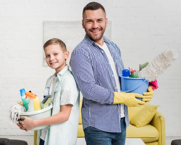 Smiley father and son posing back to back while cleaning