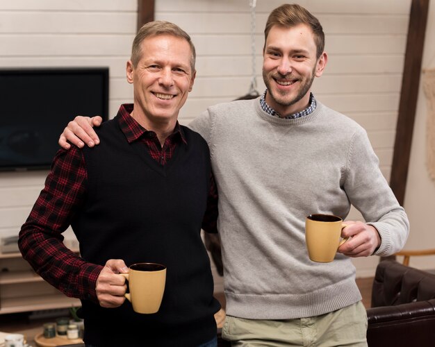 Smiley father and son posing while holding cups