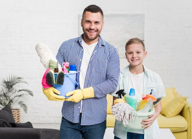 Smiley father and son posing with cleaning products