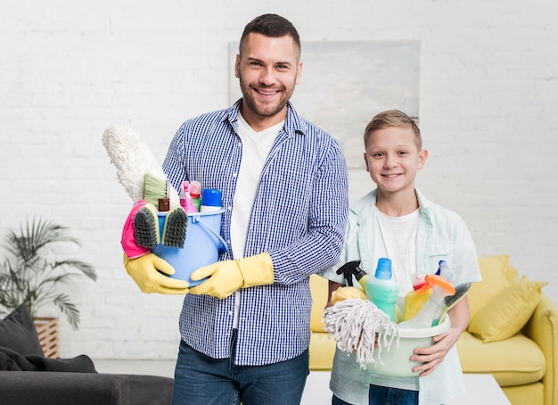 Smiley father and son posing with cleaning products