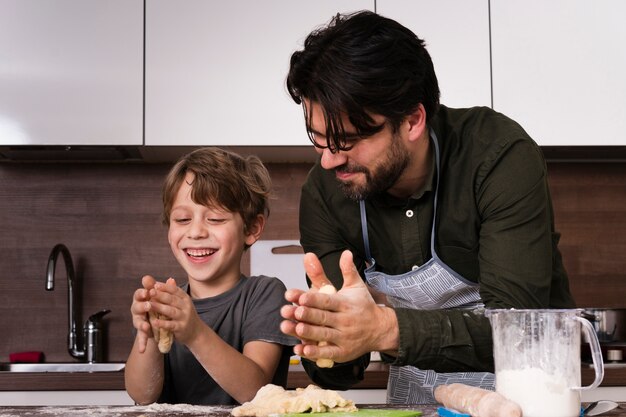 Smiley father and son rolling dough