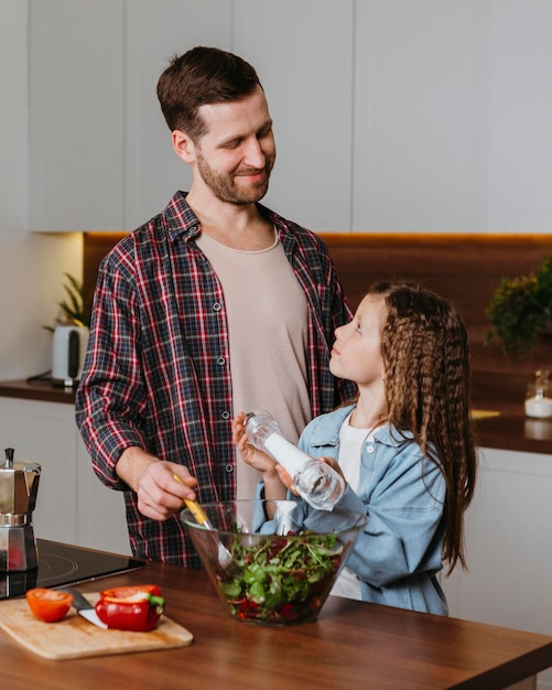 Foto gratuita padre di smiley con la figlia che prepara il cibo in cucina