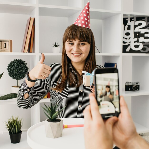 Smiley female blogger streaming birthday with smartphone