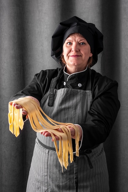 Free photo smiley female chef holding fresh pasta