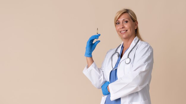 Smiley female doctor holding a vaccine syringe