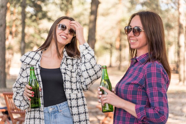 Smiley female friends drinking beer outdoors