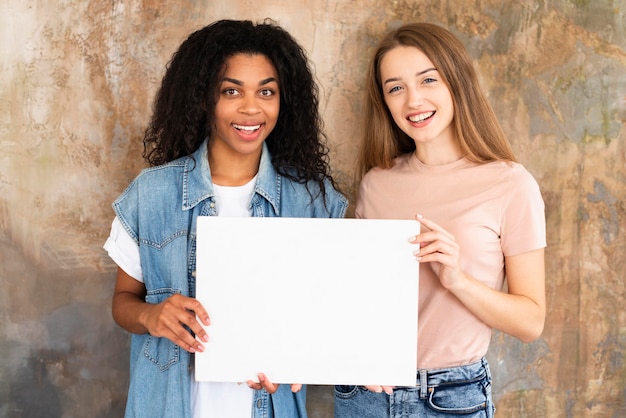 Free photo smiley female friends holding blank placard