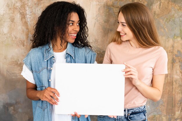 Smiley female friends holding blank placard