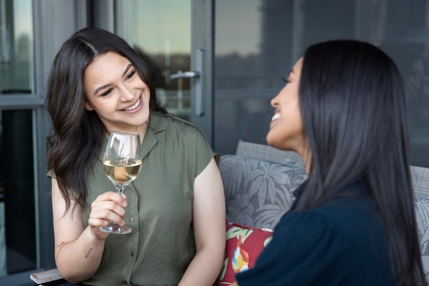 Smiley female friends spending time together and drinking wine at a terrace