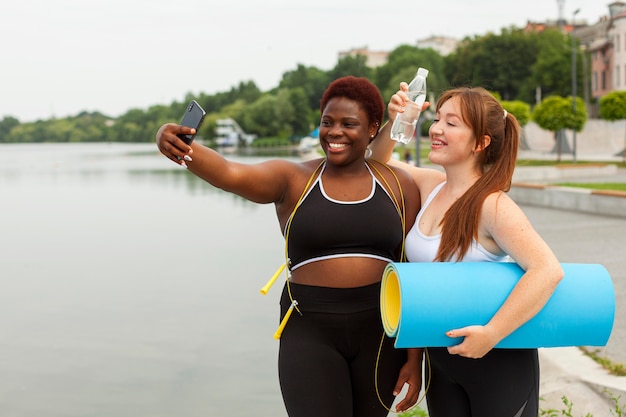 屋外で運動しながらselfieを取ってスマイリーの女性の友人