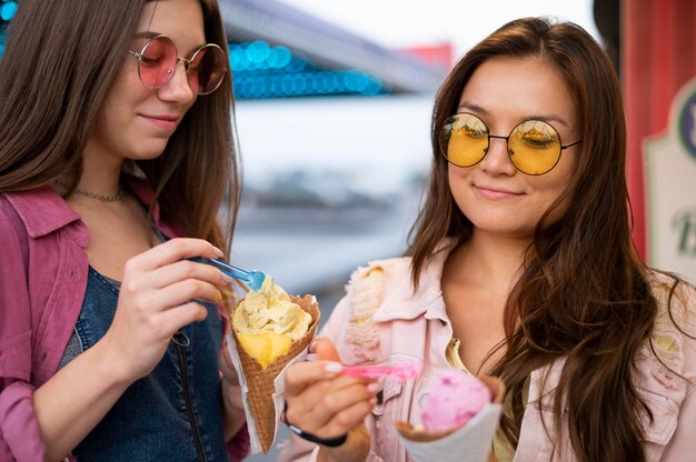 Smiley female friends with sunglasses eating candy