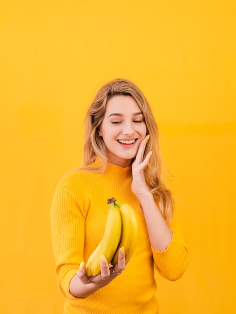 Free photo smiley female holding bananas