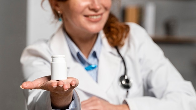 Free photo smiley female physician holding holding bottle of medicine