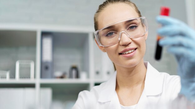 Smiley female researcher in the laboratory with test tube and copy space