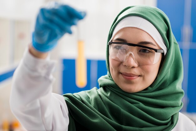 Smiley female scientist with hijab holding substance