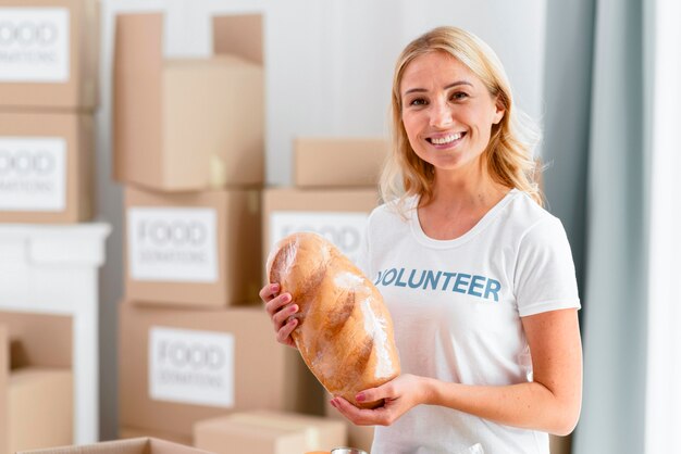 Smiley female volunteer holding bread for donation