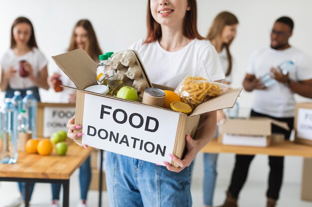 Smiley female volunteer holding donations box with food