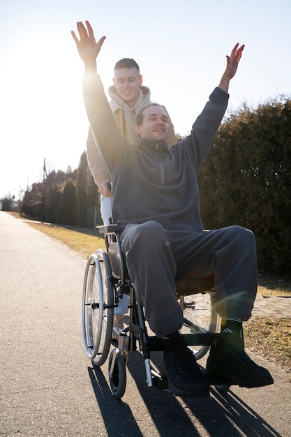 Smiley friend helping disabled man full shot