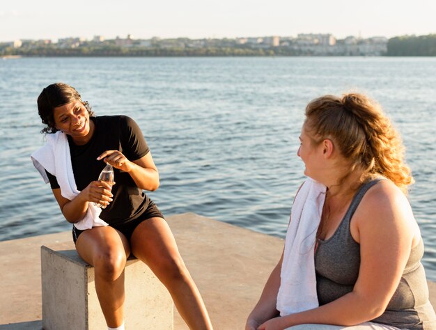 Smiley friends conversing by the lake after working out