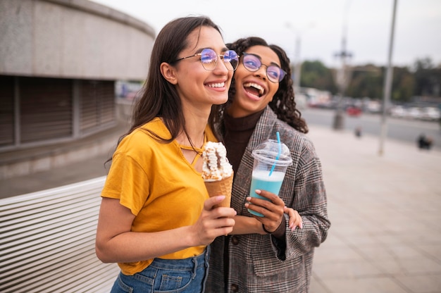 Smiley friends having fun together outdoors with milkshakes