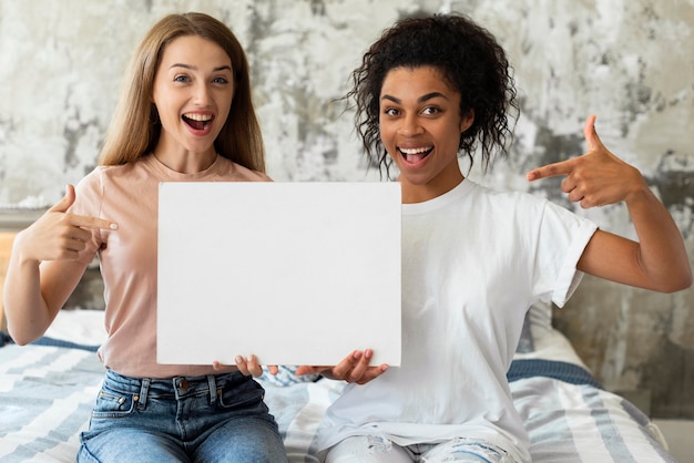 Smiley friends holding and pointing at blank placard