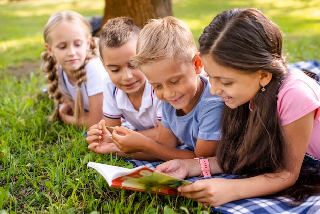 Free photo smiley friends sitting on blanket and reading