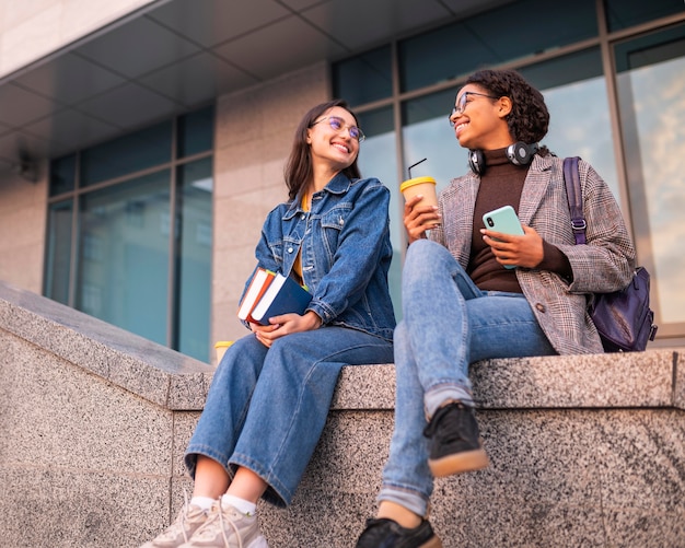 Free photo smiley friends with books having coffee together