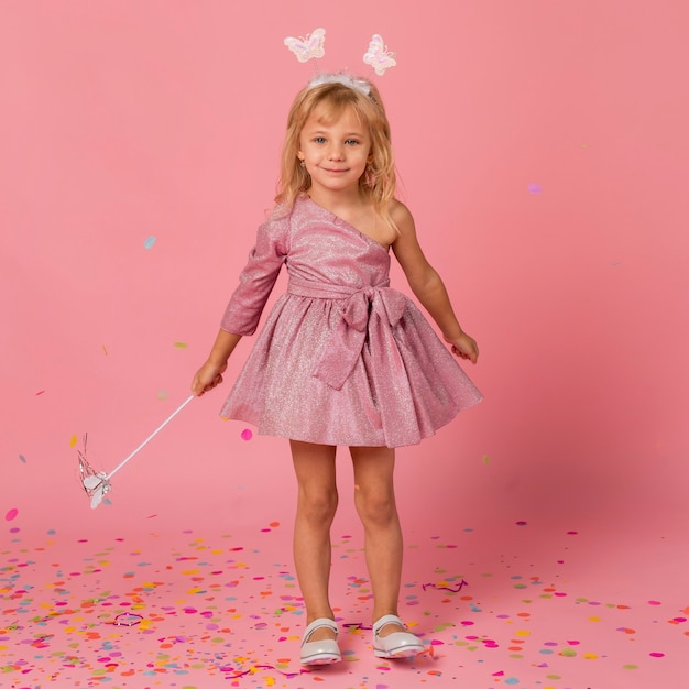 Smiley girl in fairy costume with confetti and wand