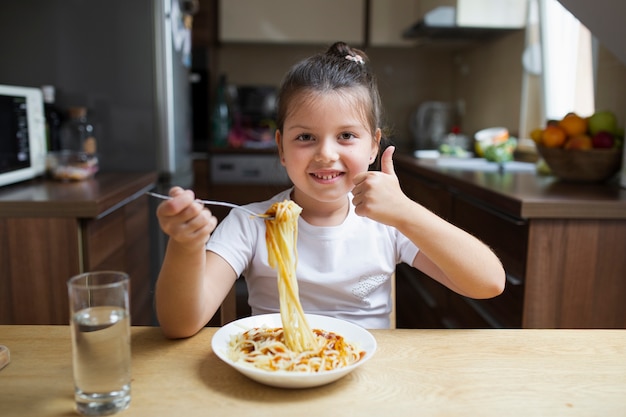 昼食時にパスタを持つスマイリーの女の子