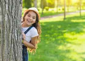 Free photo smiley girl hiding behind a tree